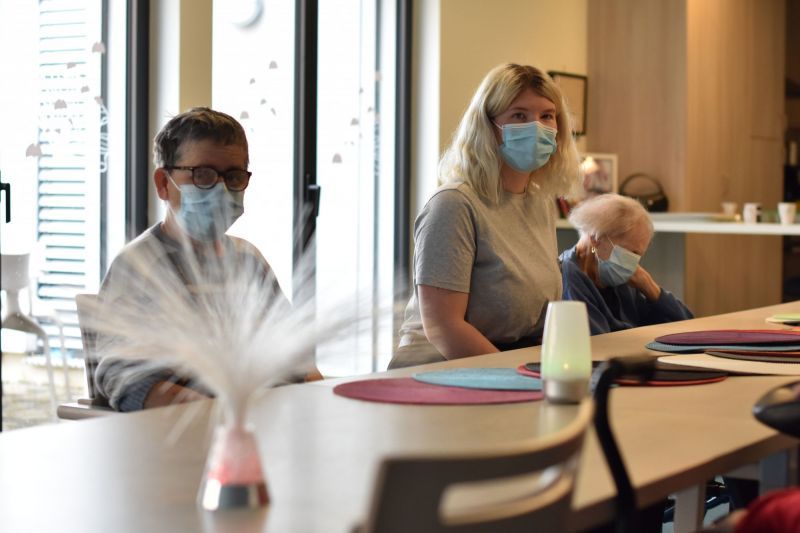 Un groupe de personnes portant des masques faciaux sont assises à une table.