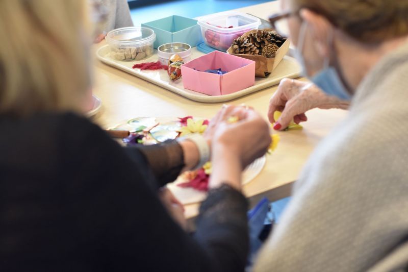 Un groupe de personnes sont assises à une table et fabriquent des objets artisanaux.