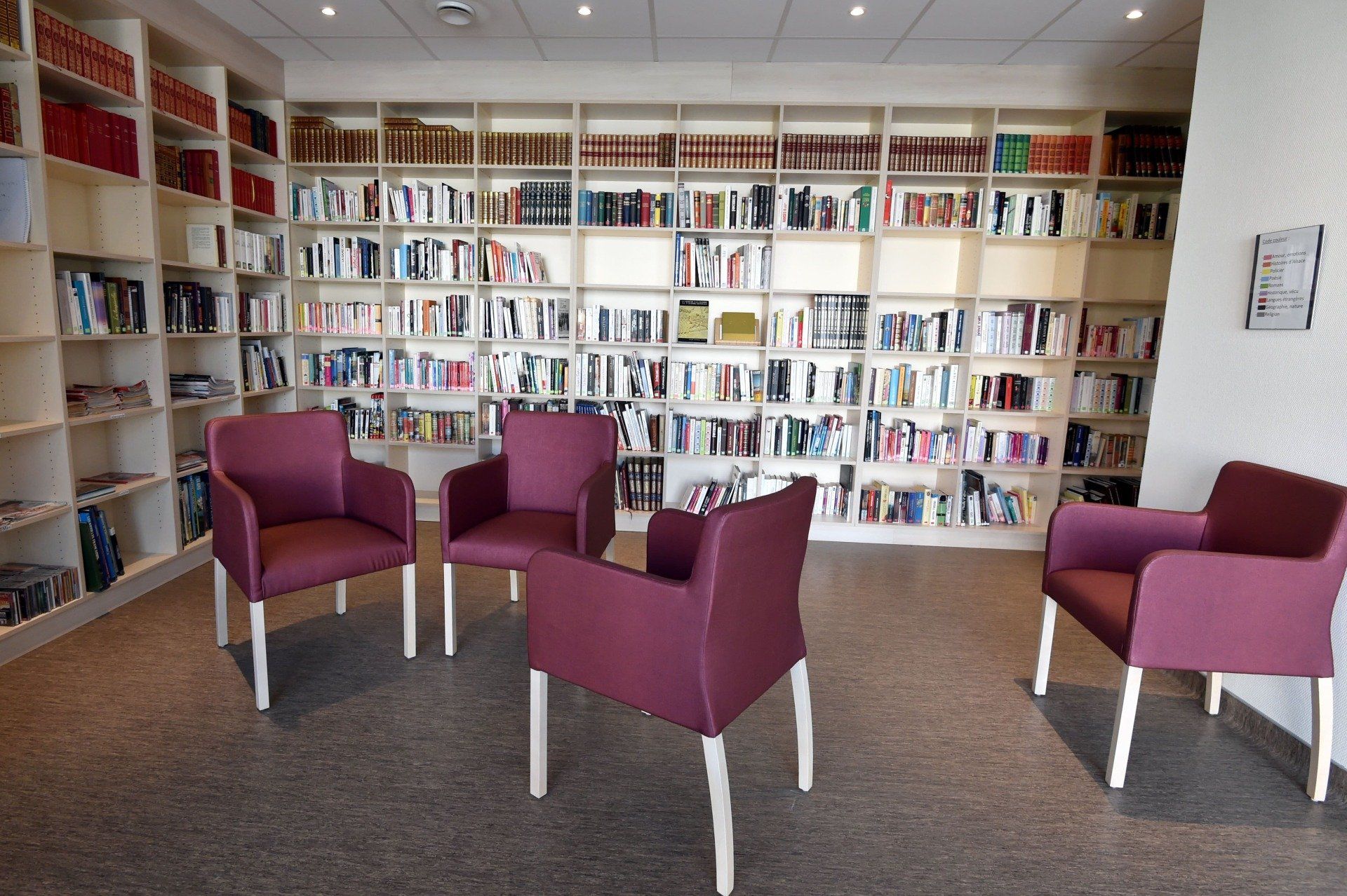 Un groupe de chaises violettes sont assises devant une étagère.