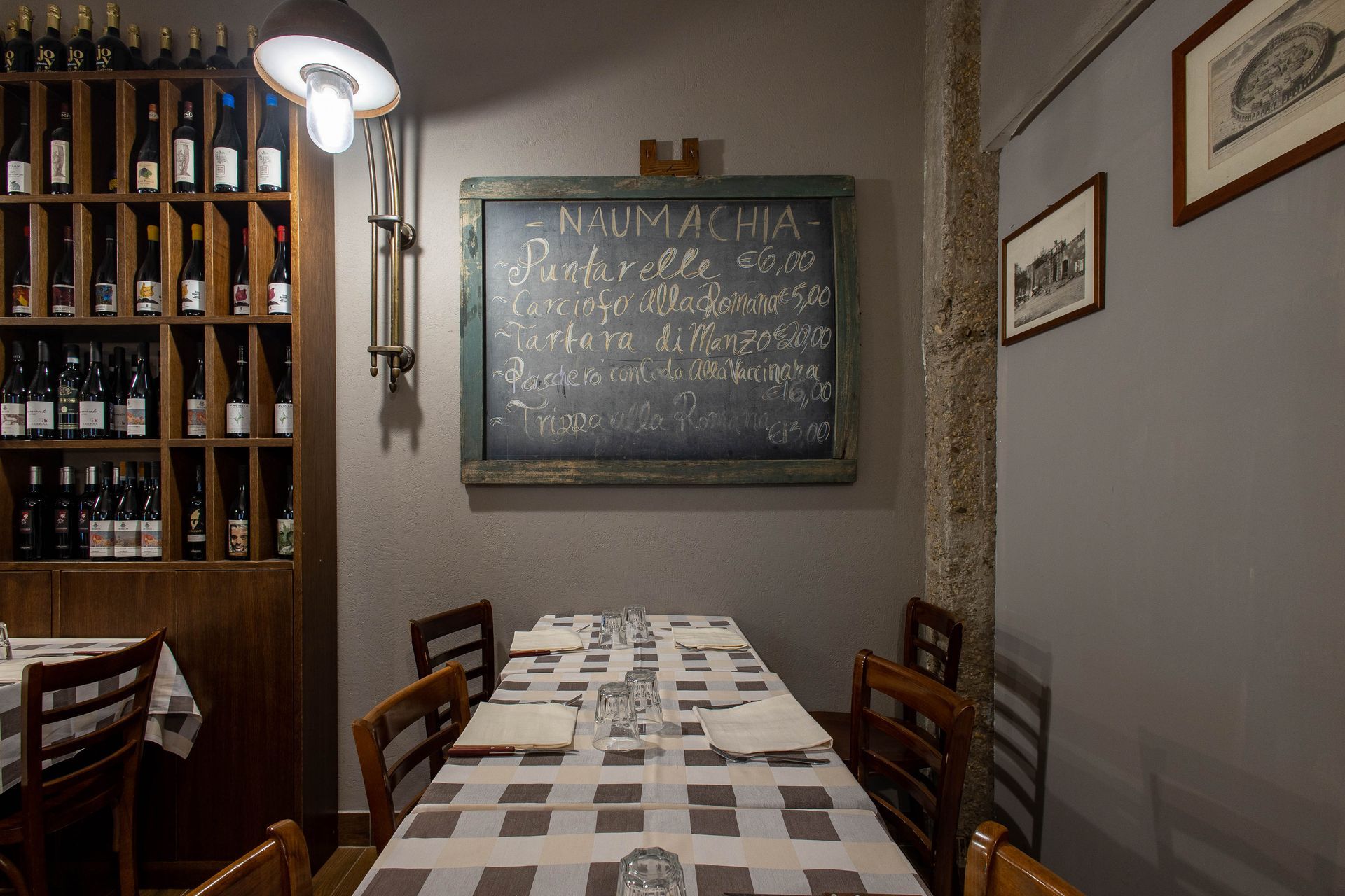 Accogliente sala da pranzo del ristorante con tavolo a scacchi, sedie in legno, scaffali per il vino e lavagna con il menù.