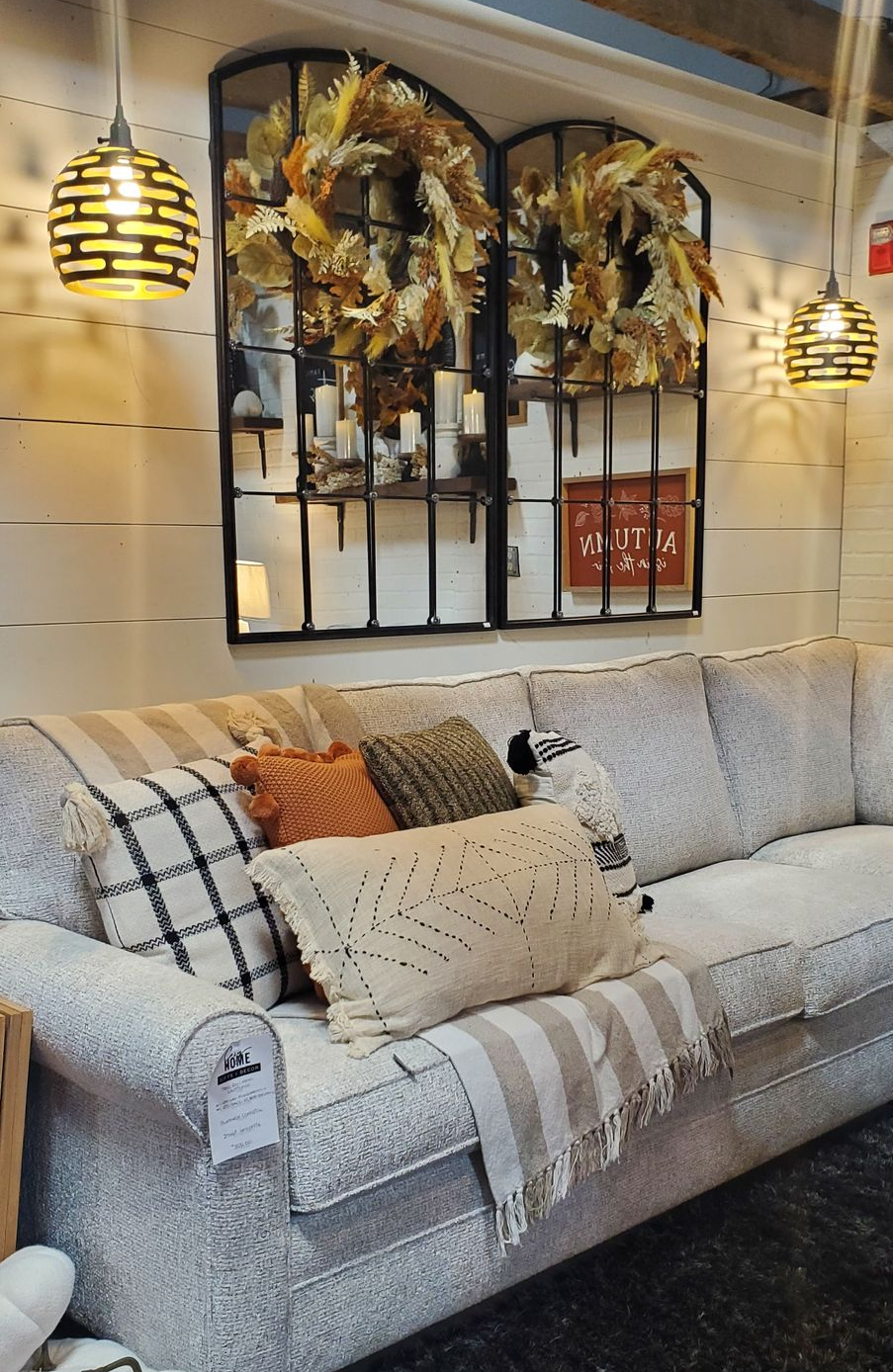 A couch with pillows and a mirror above it. A couch with pillows and a mirror above it.