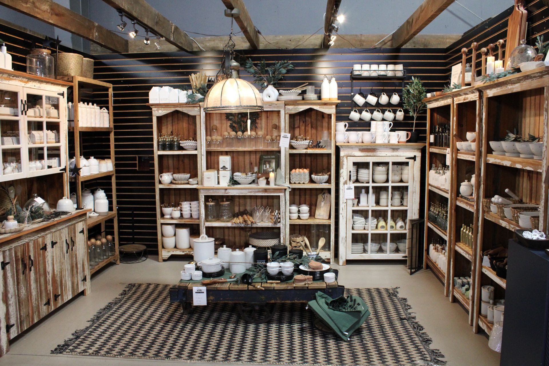 Retail store interior with rustic wooden shelves displaying home goods and decor.