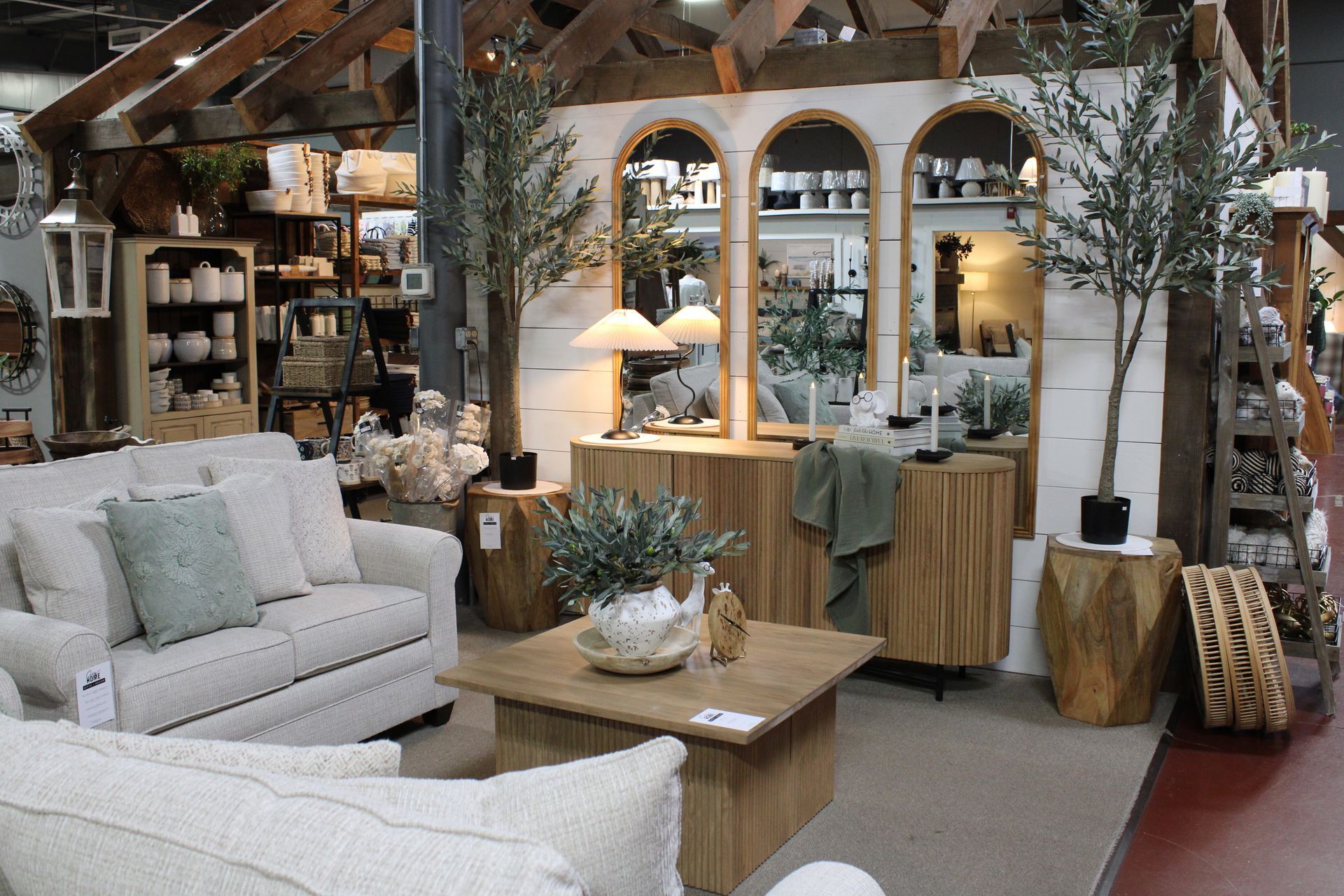 A home decor store display with a wooden dining table, greenery, ornaments, and a warm lighting set.