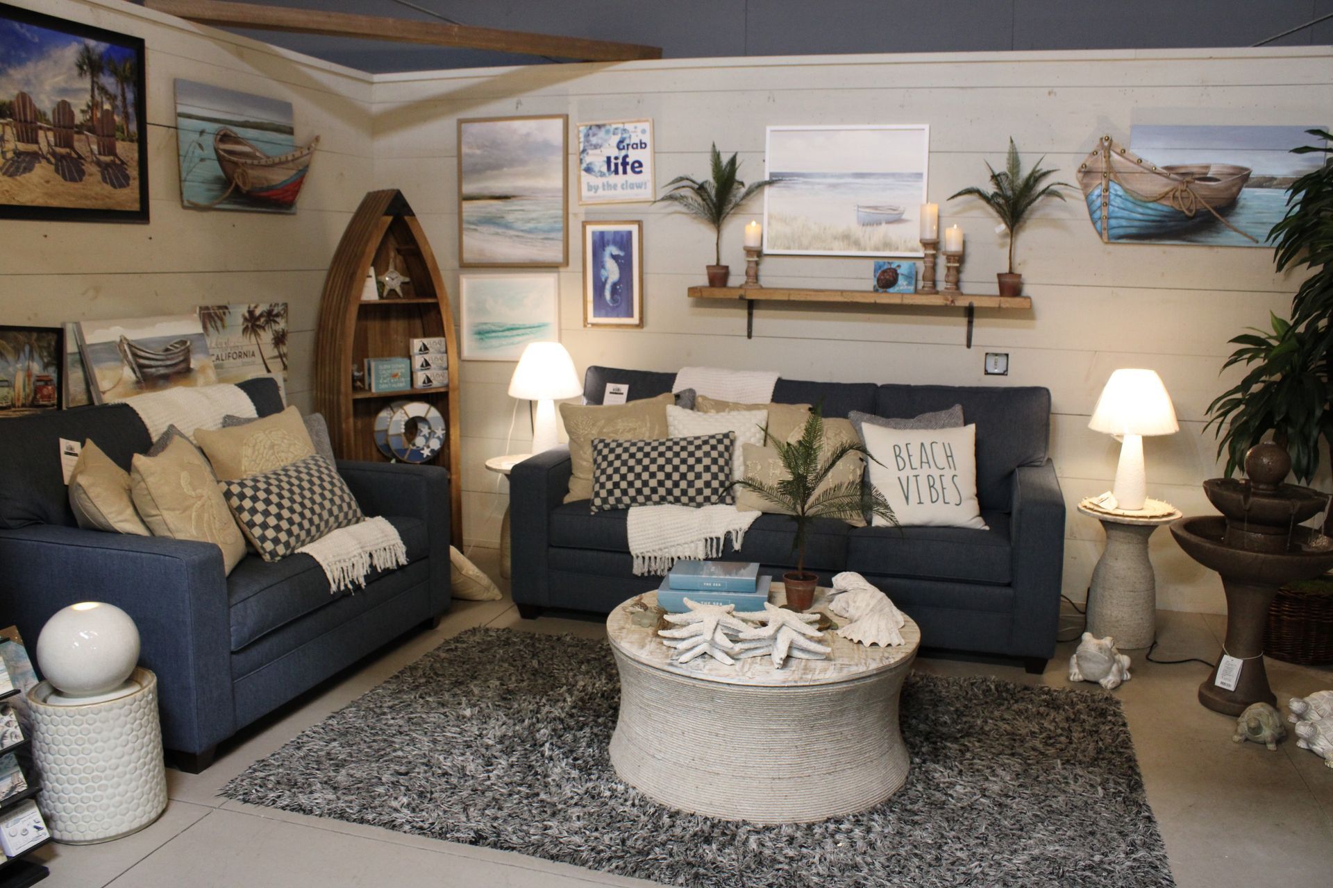 Coastal-themed shop interior with sofa, shelves, and decorative beach signs.