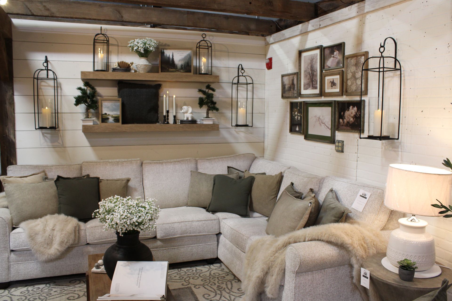 Living room furniture display with gray sofa and armchair, rustic decor, lanterns, and artwork.