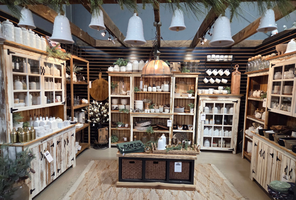 Rustic home goods display with shelves of white dishes, wood cabinets, and hanging lights.