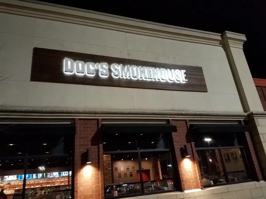 Nighttime exterior of Joe's Smokhouse restaurant with illuminated sign above brick storefront.