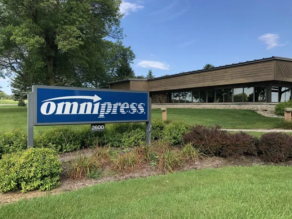 Omnipress sign in front of a low office building on a landscaped lawn