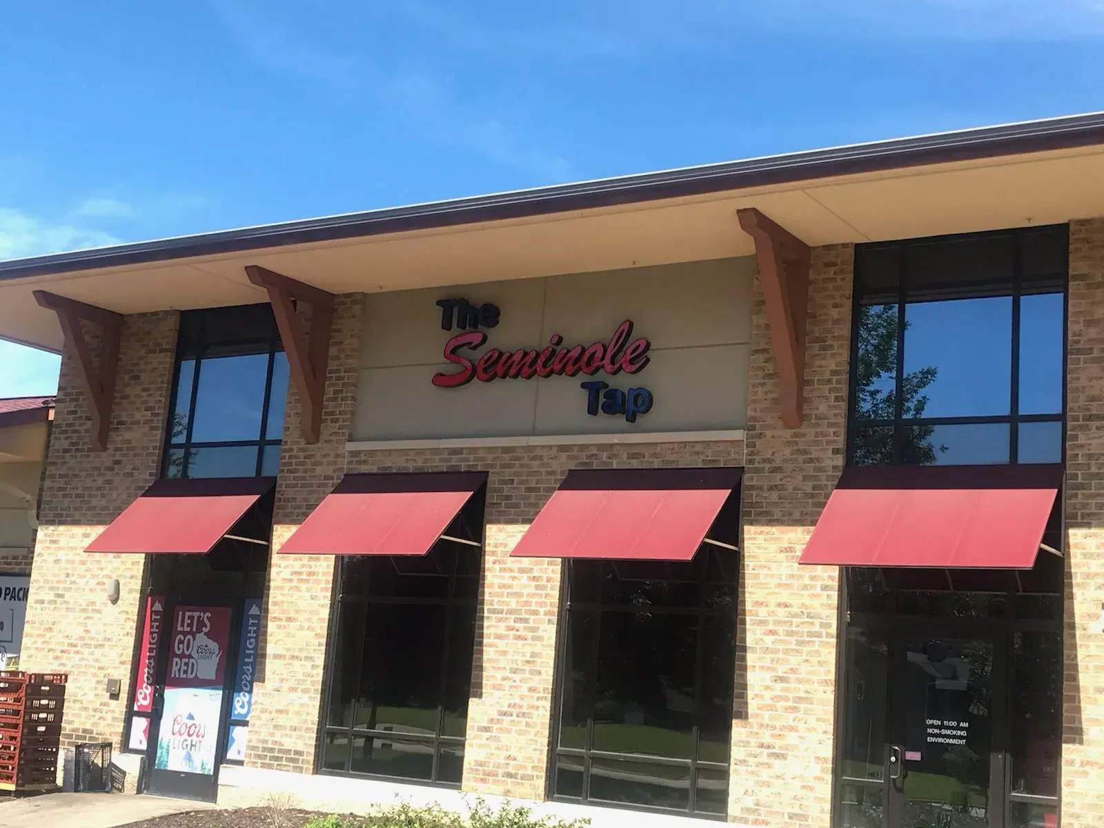 Storefront of The Sandwich Shop with red awnings and large windows on a sunny day