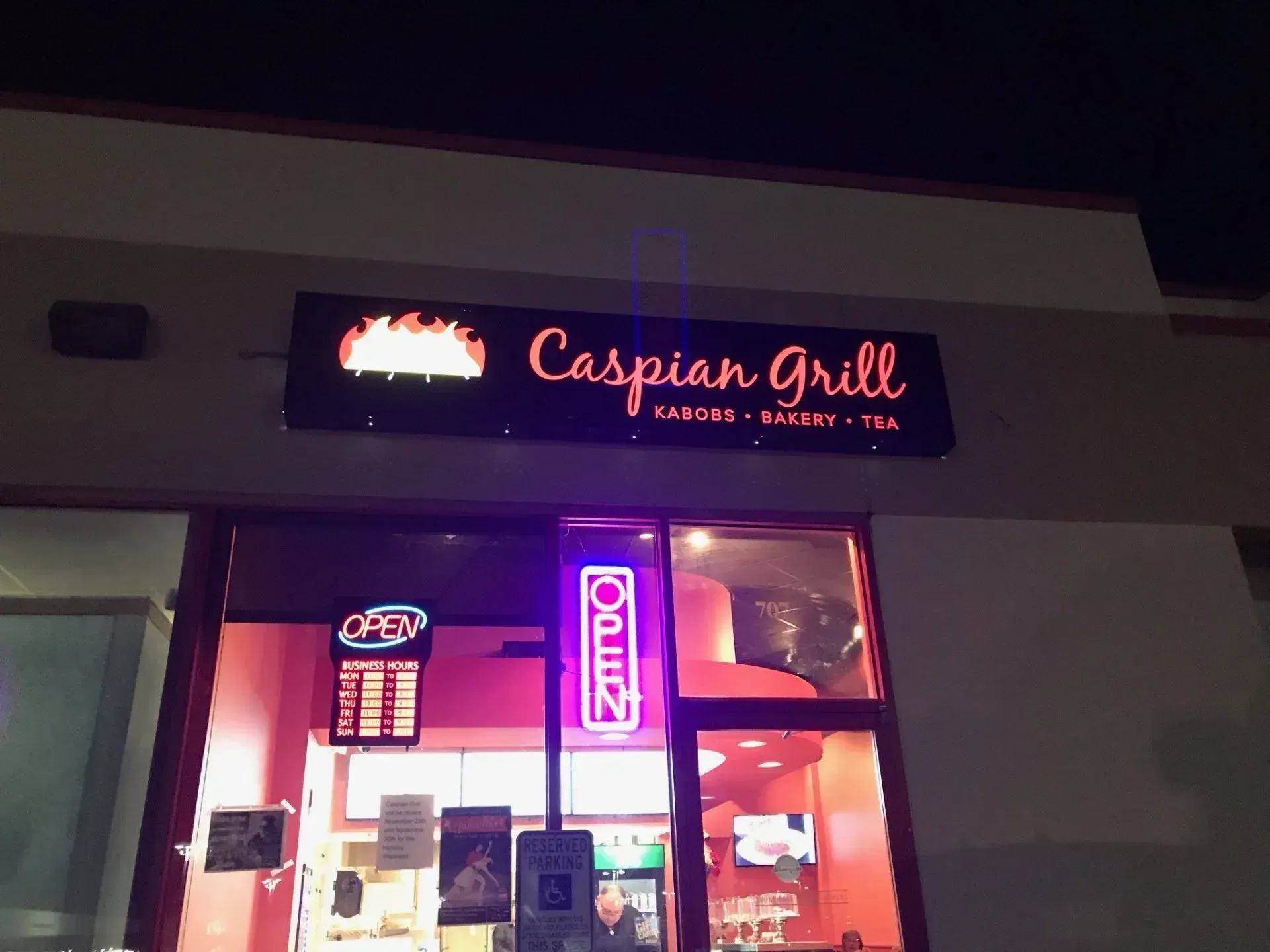 Caspian Grill storefront at night with glowing red sign and purple open neon sign