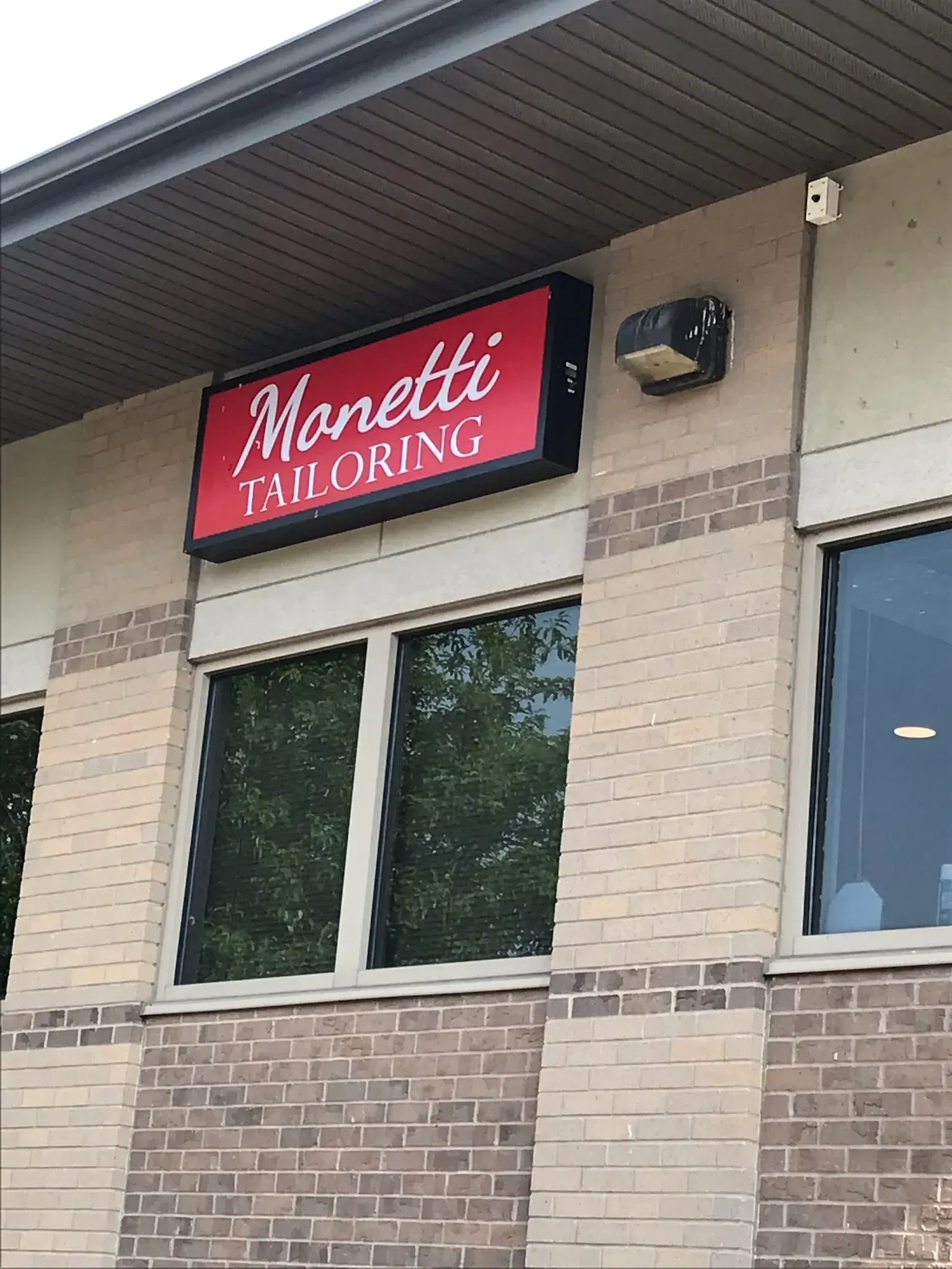 Manetti Flooring storefront sign on a tan brick building with windows.