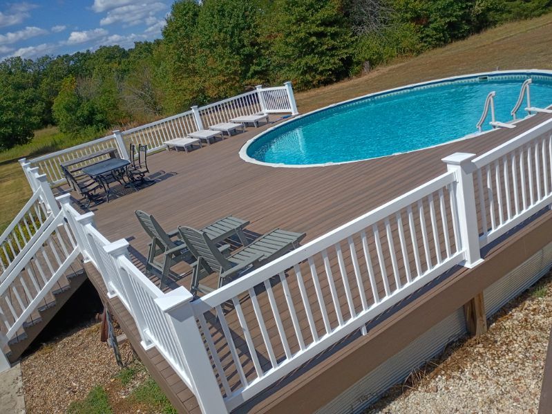 Backyard deck with a round above-ground pool, white railing, and lounge chairs in sunlight.
