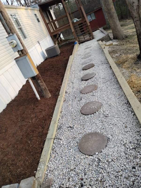 Gravel garden path with stepping stones beside a house and wooden deck