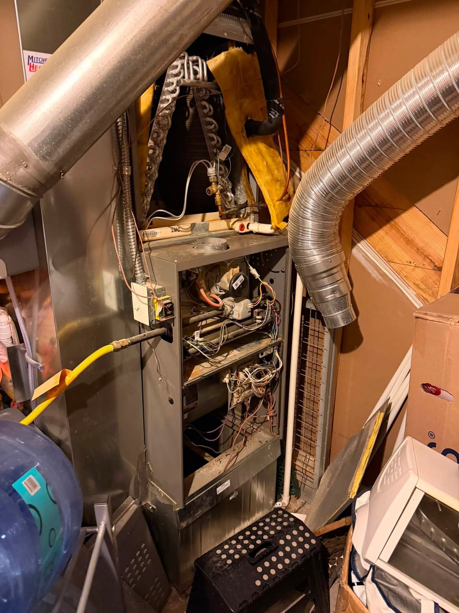Utility room with a furnace, water heater, and exposed white and metal pipes along the wall.