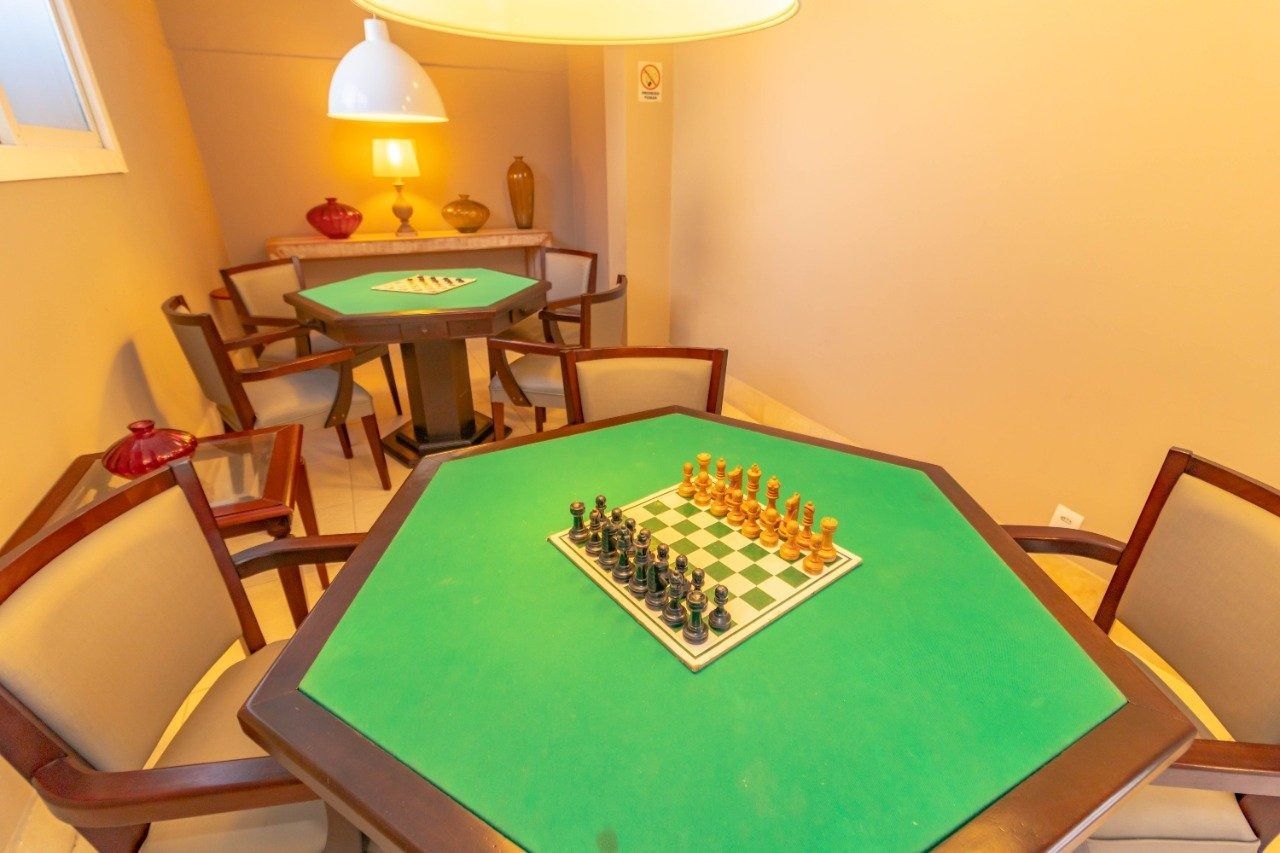 Dois tabuleiros de xadrez sobre mesas verdes em uma sala de jogos com iluminação aconchegante