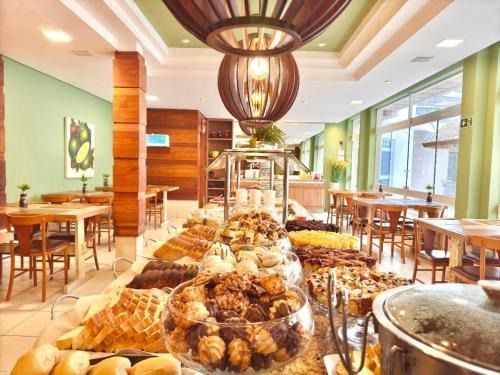 Buffet num café moderno e luminoso, com mesas, cadeiras de madeira e luminárias pendentes
