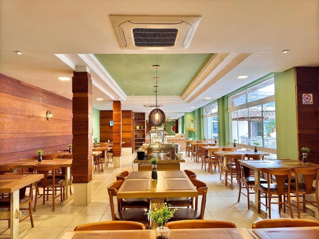 Sala de jantar moderna de restaurante, com mesas e cadeiras de madeira e grandes janelas sob uma iluminação aconchegante