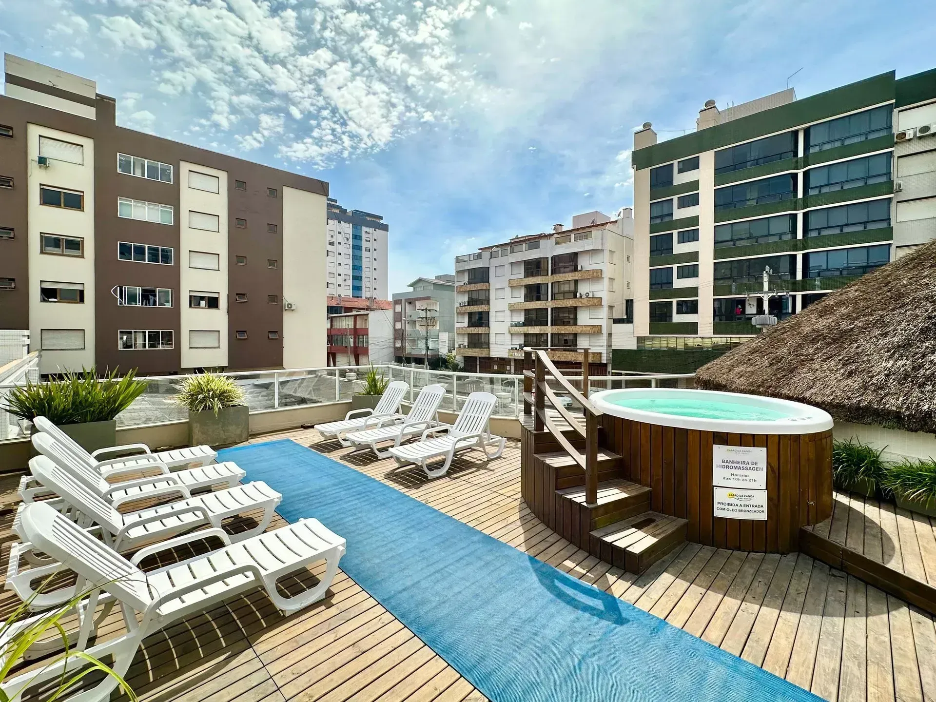 Terraço com piscina no rooftop, espreguiçadeiras, banheira de hidromassagem e edifícios da cidade sob um céu azul