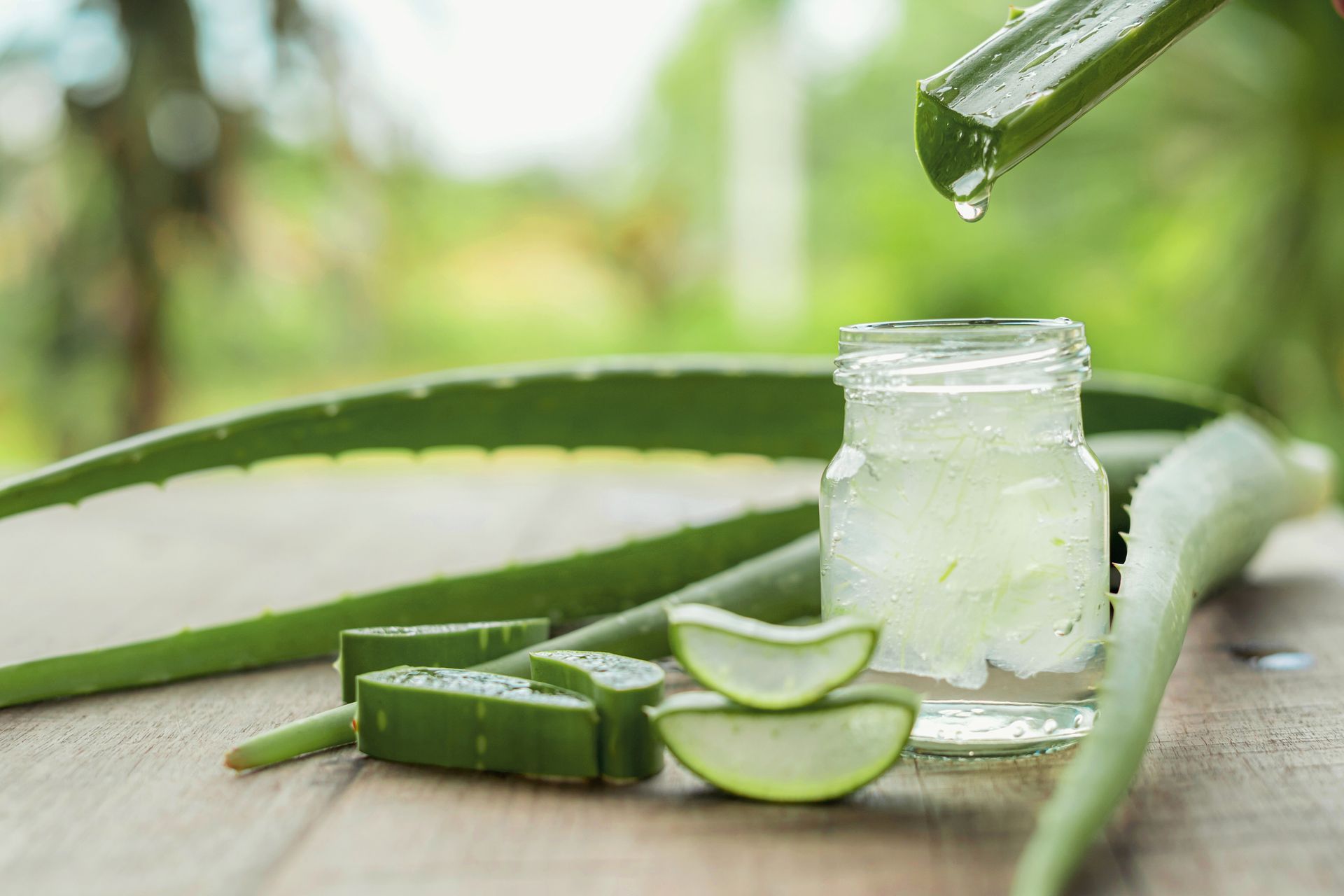 Aloe Vera wird in ein Glas auf einem Holztisch gegossen.