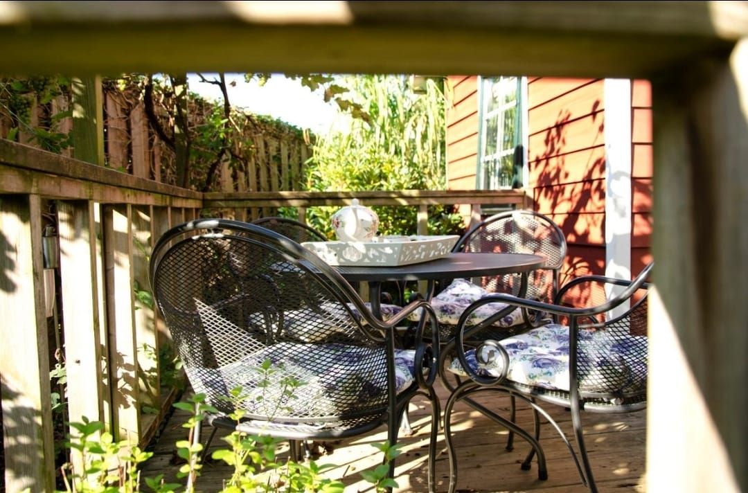 Buitenterras met zwart metalen meubilair, een ronde tafel en een vogelbad.