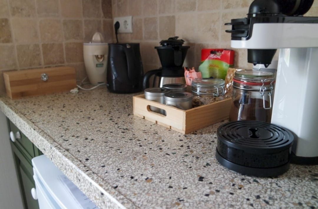 Keukenblad met diverse koffiezetapparaten: espressomachine, koffiezetapparaat en voorraadpotten.