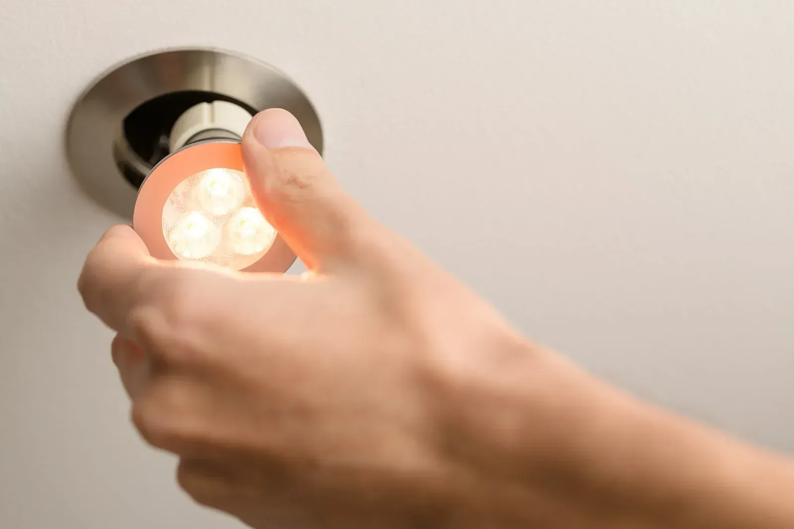 A person is changing a light bulb in a ceiling light.