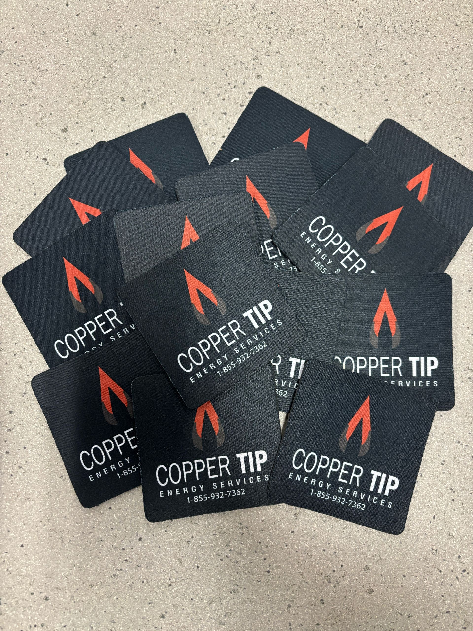 Several black Copper Tip cards with red arrow logos scattered on a speckled surface