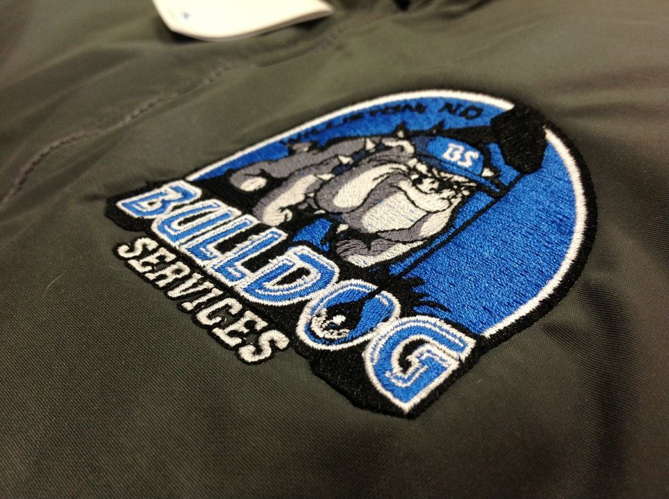 Bulldog Services logo embroidered on a black shirt with a blue circular design