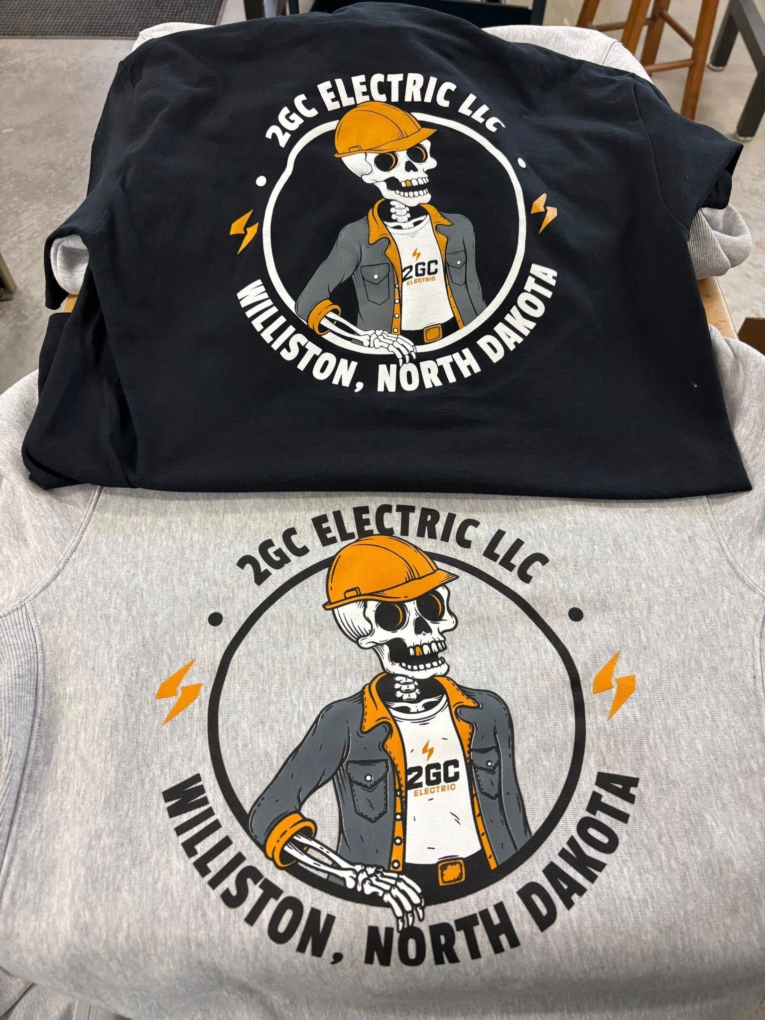 Black bag and gray shirt with a skull electrician logo reading “J&C Electric LLC, Williston, North Dakota.”