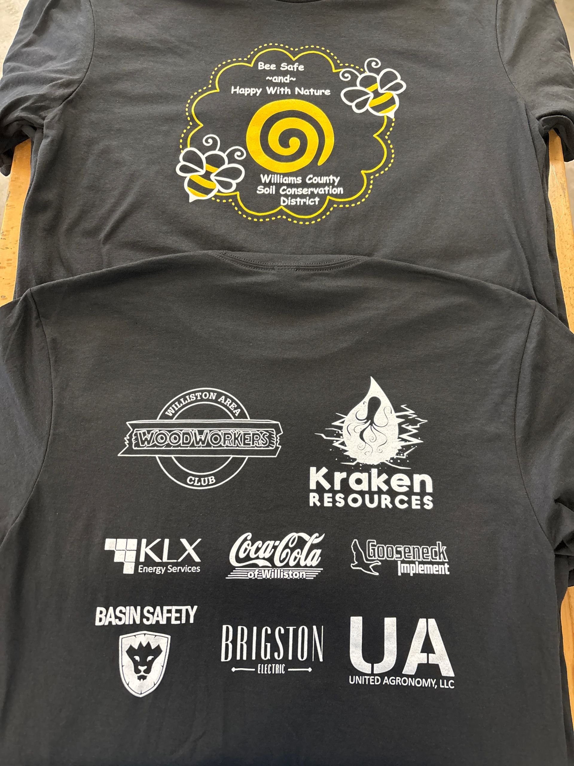 Black T-shirt with yellow spiral logo and white sponsor logos printed on the front.