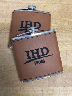 Two tan IHD Solids metal canisters with silver lids on a wooden surface.