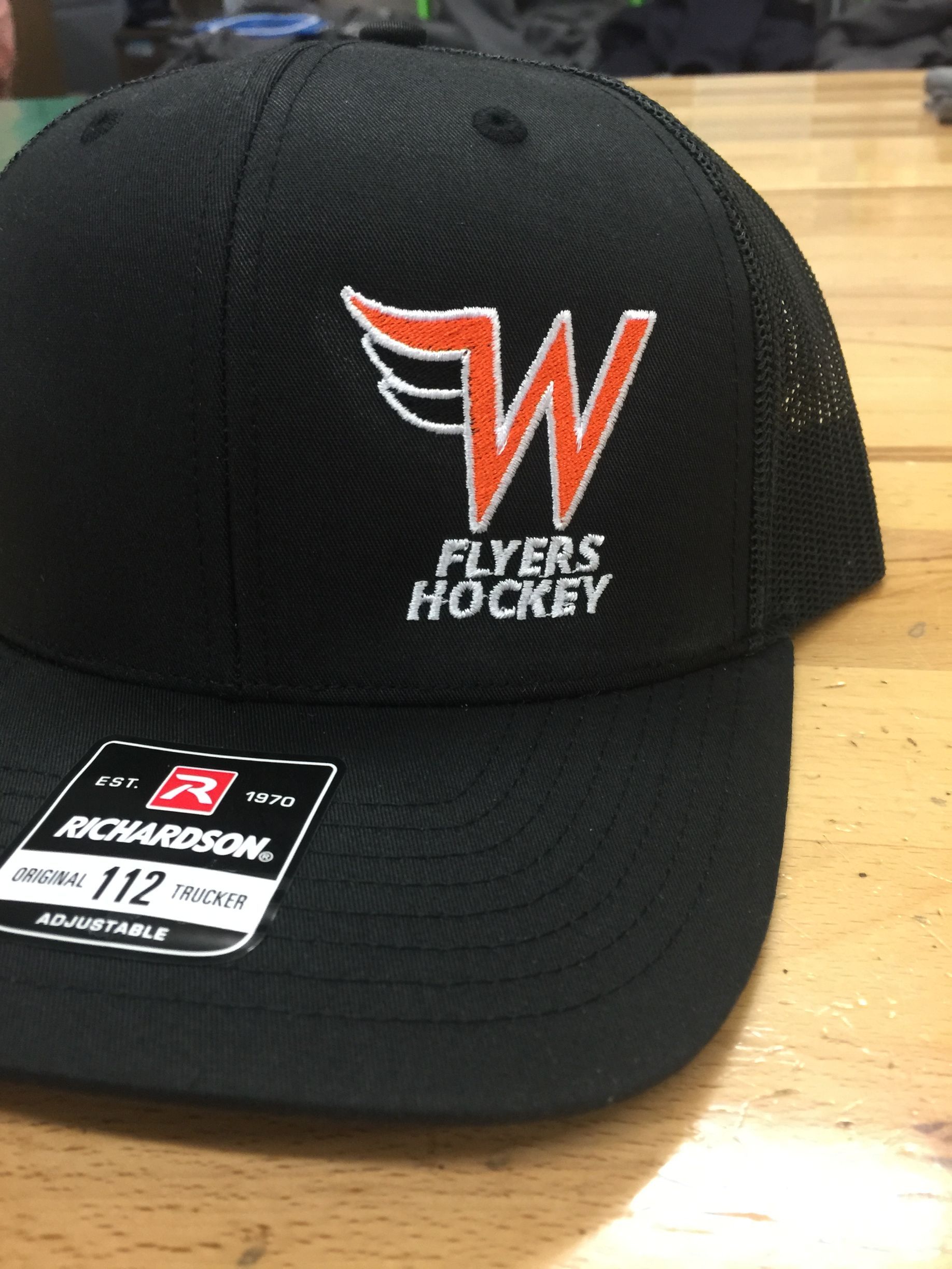 Black Flyers Hockey cap with red-and-white logo on a wooden table