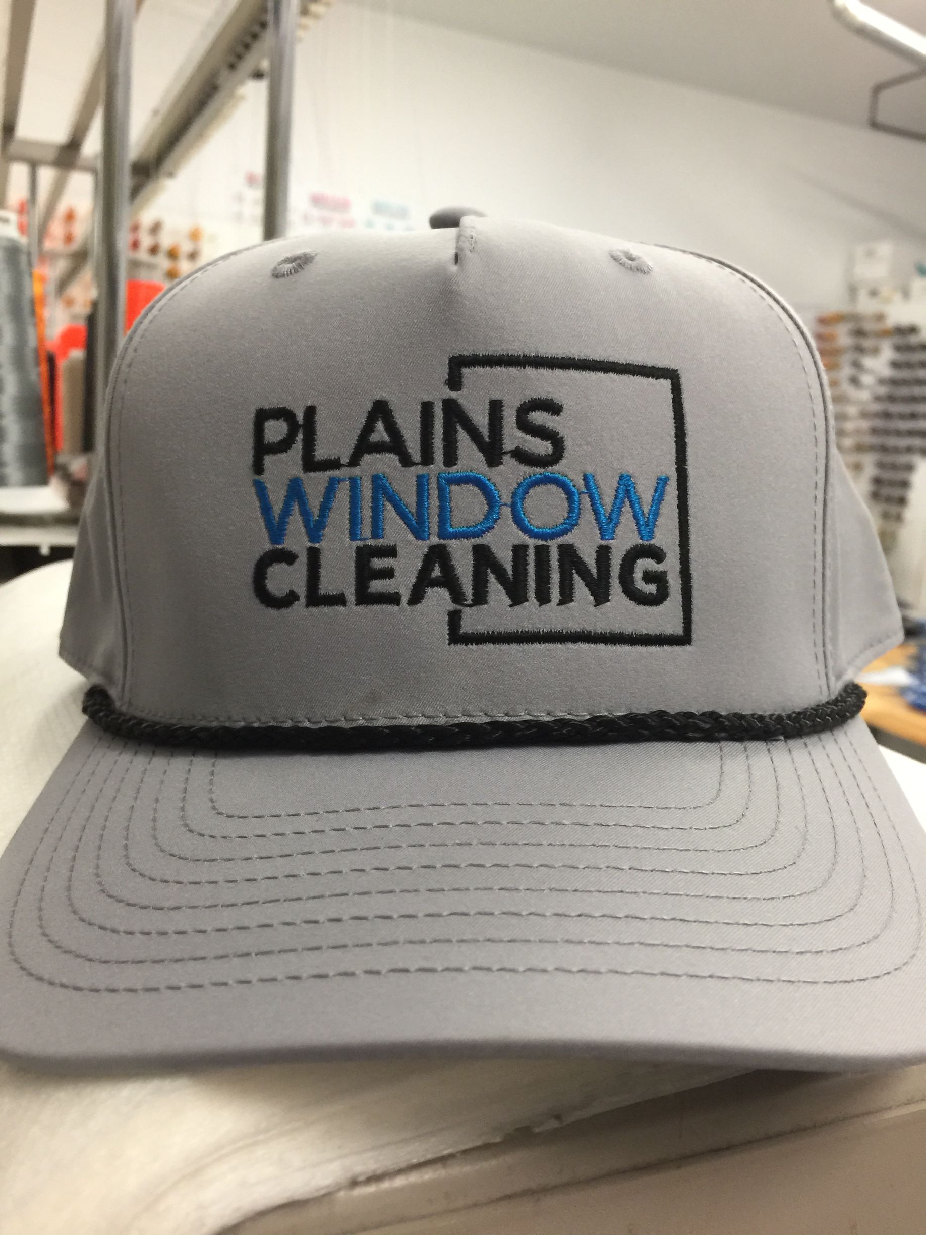 Gray “Plains Window Cleaning” trucker hat on a table.