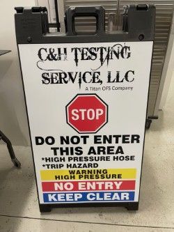 C&H Testing Service safety sign with red STOP and warning labels: “Do Not Enter,” “High Pressure Hose Trip Hazard,” “Keep Clear”