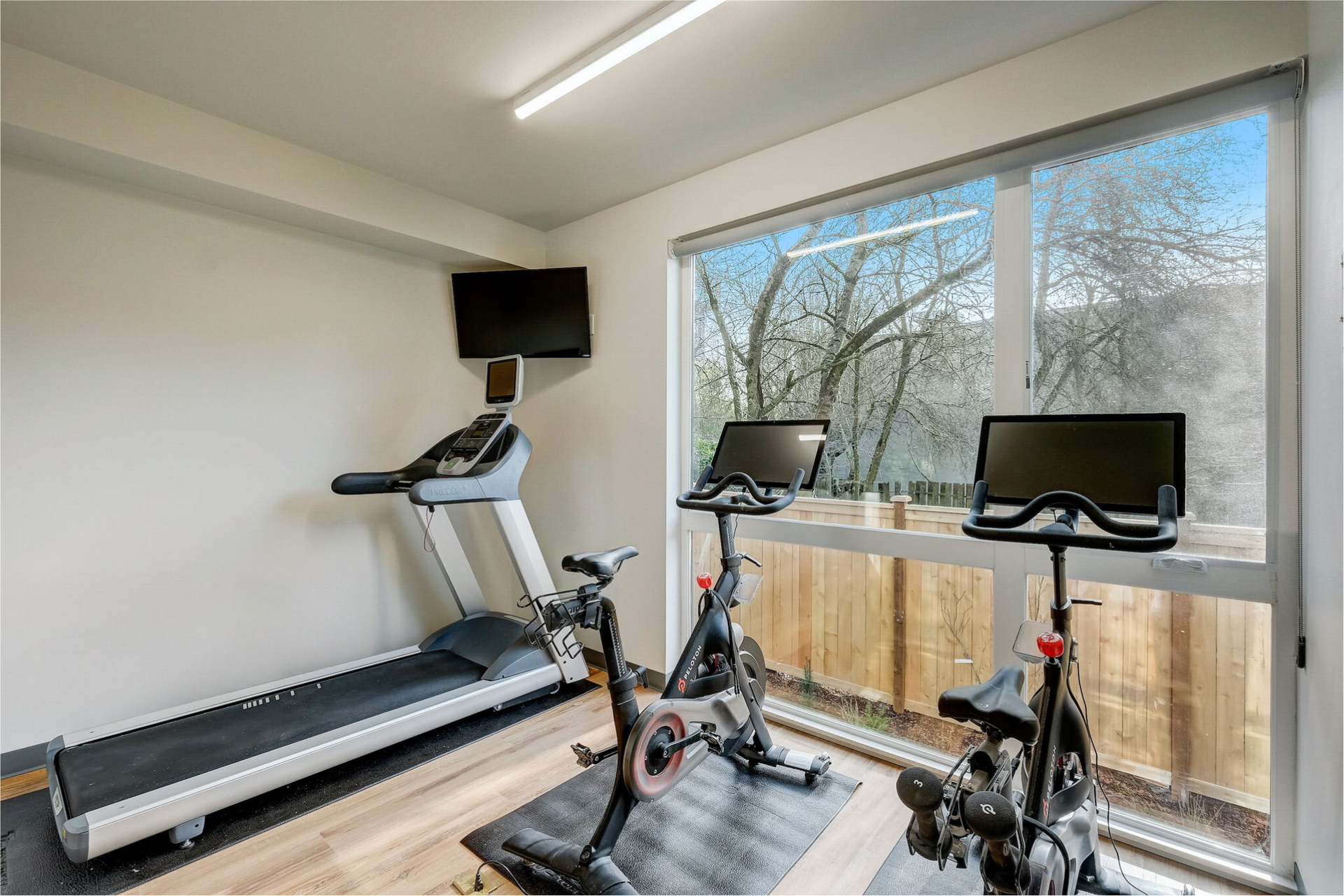 Community fitness room with two peleton bicycles, treadmill, and TV