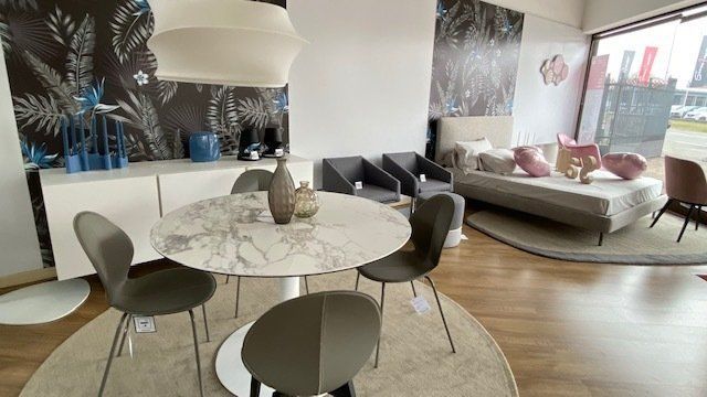 Esposizione della sala da pranzo con un tavolo rotondo in marmo, sedie grigie e una credenza bianca