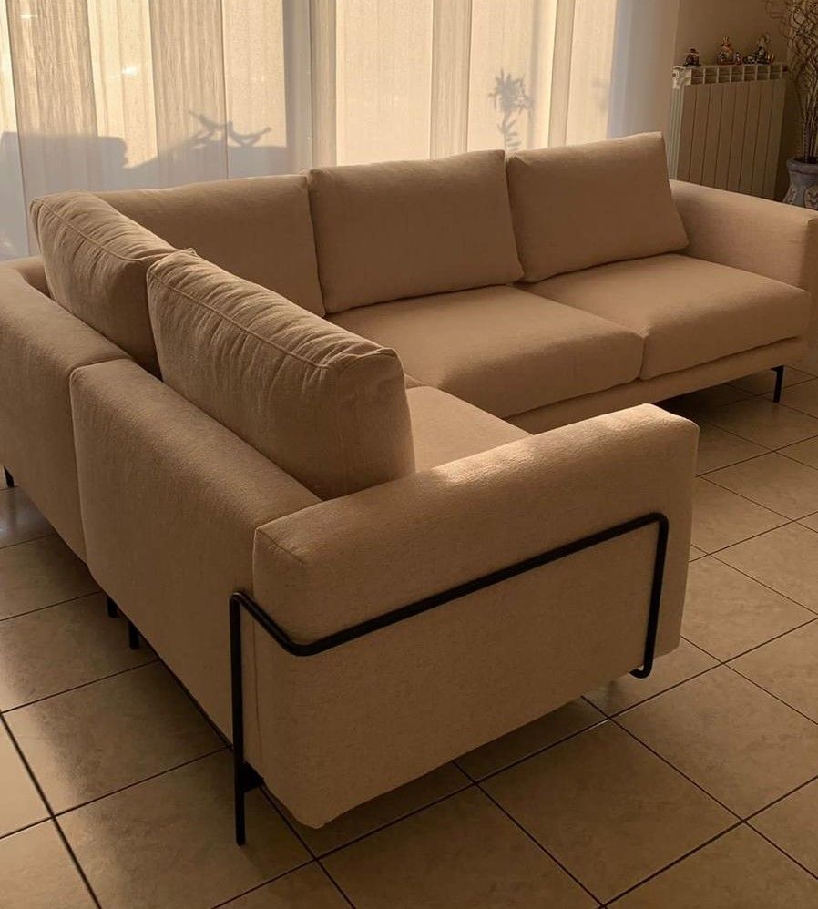 Divano componibile beige con struttura in metallo nero in una stanza soleggiata.
