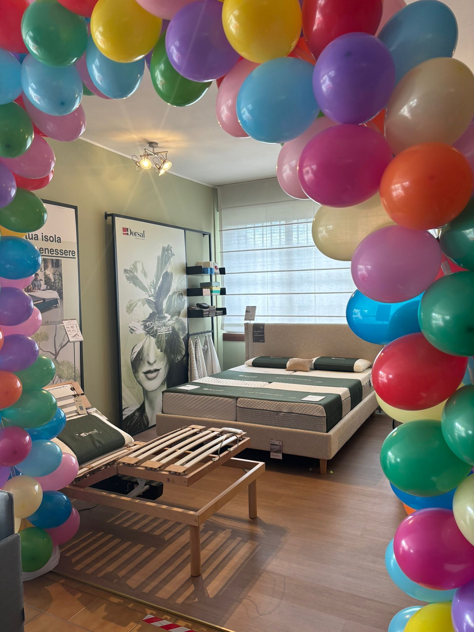 Palloncini colorati incorniciano l'esposizione di un letto in uno showroom,