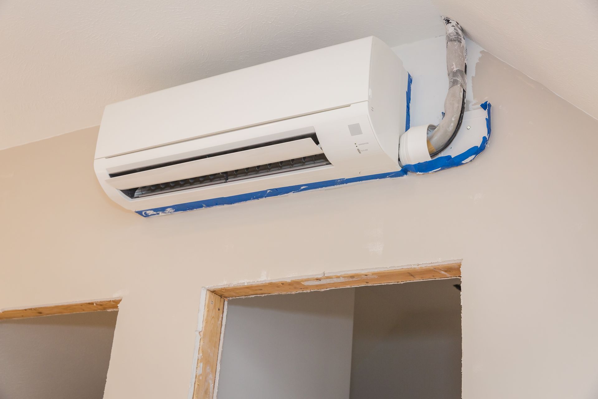 A Man Is Working on An Air Conditioner on The Side of A Building — Bryan, TX — Air Concept Services