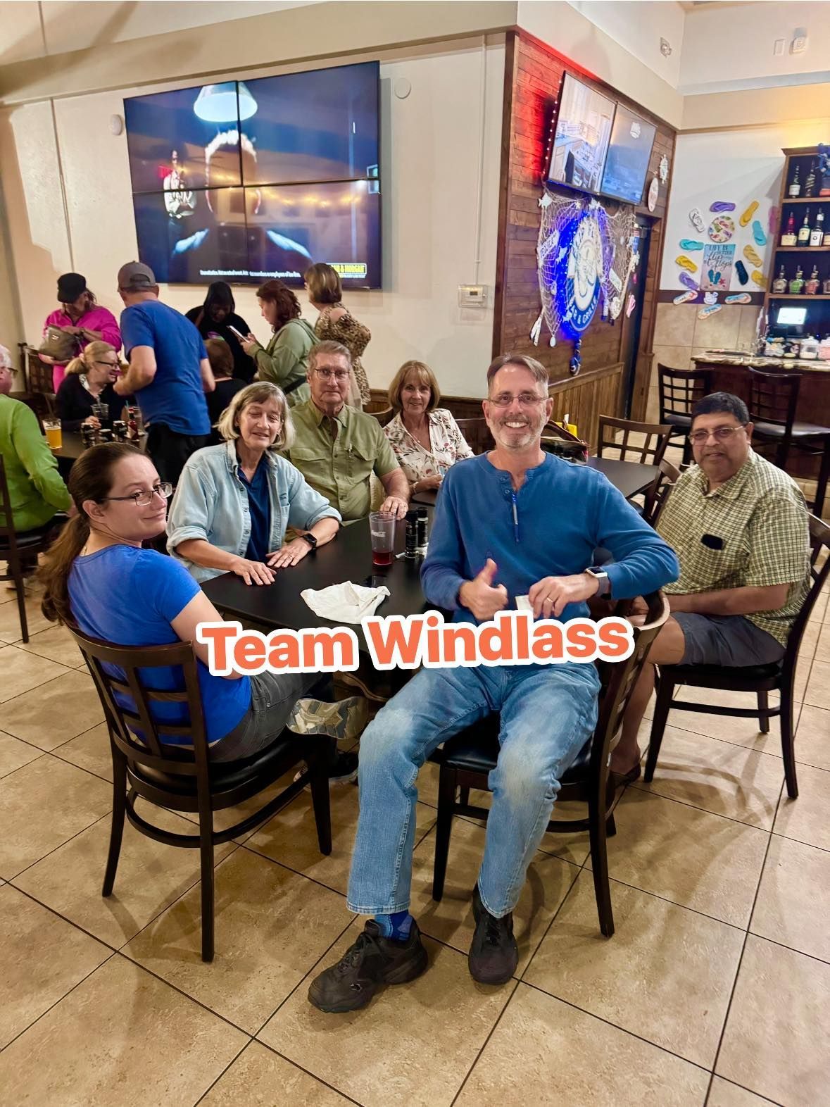 Group of people at a restaurant, some smiling, with the words 