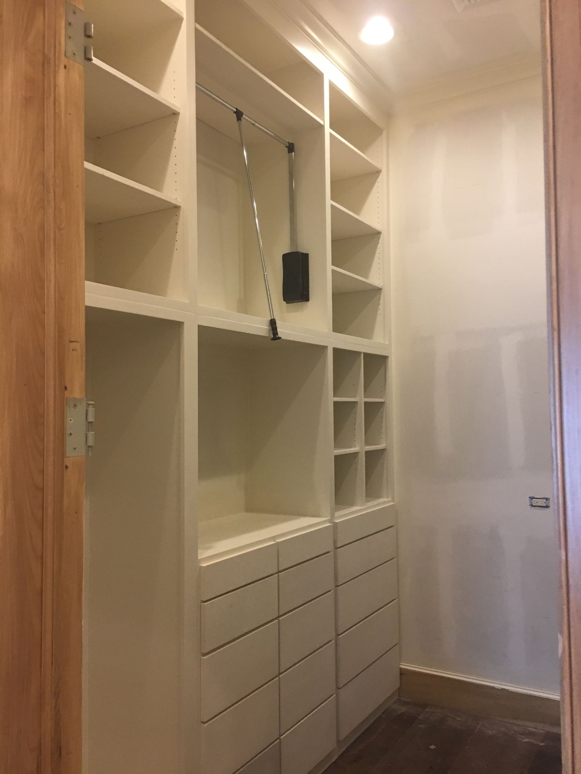 A walk in closet with lots of shelves and drawers.