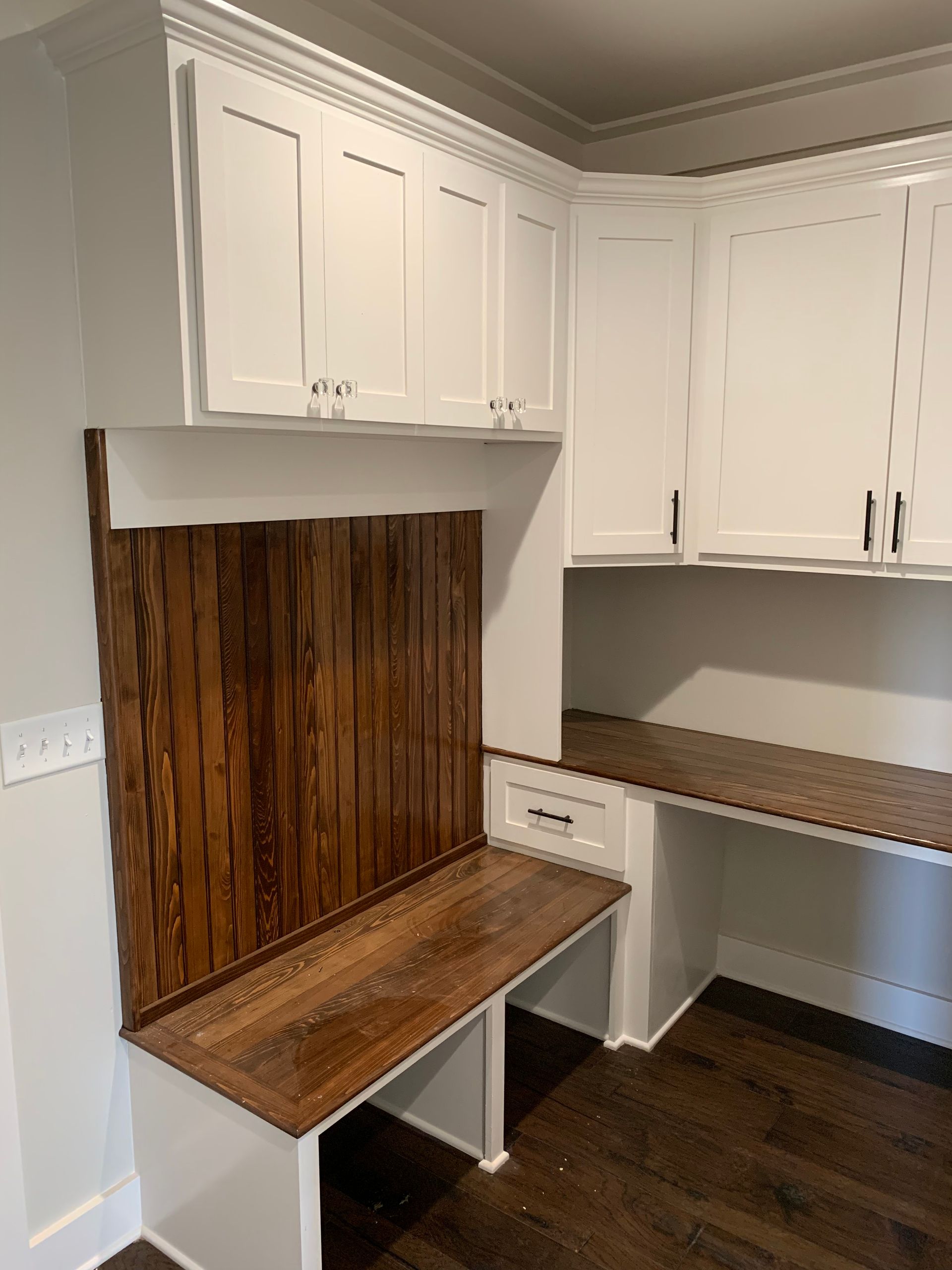 A kitchen with white cabinets and a wooden bench.