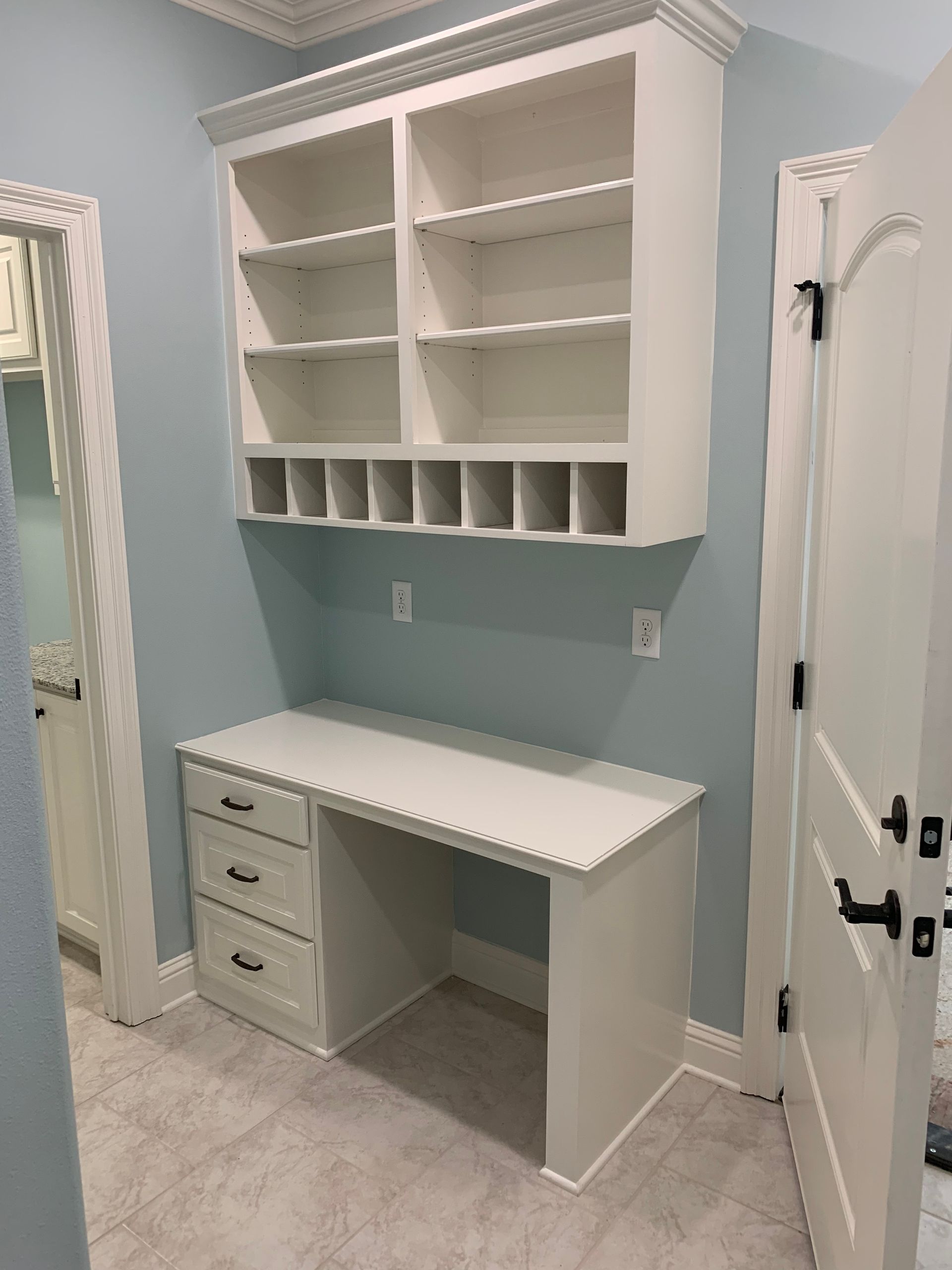 A room with a desk and shelves on the wall.