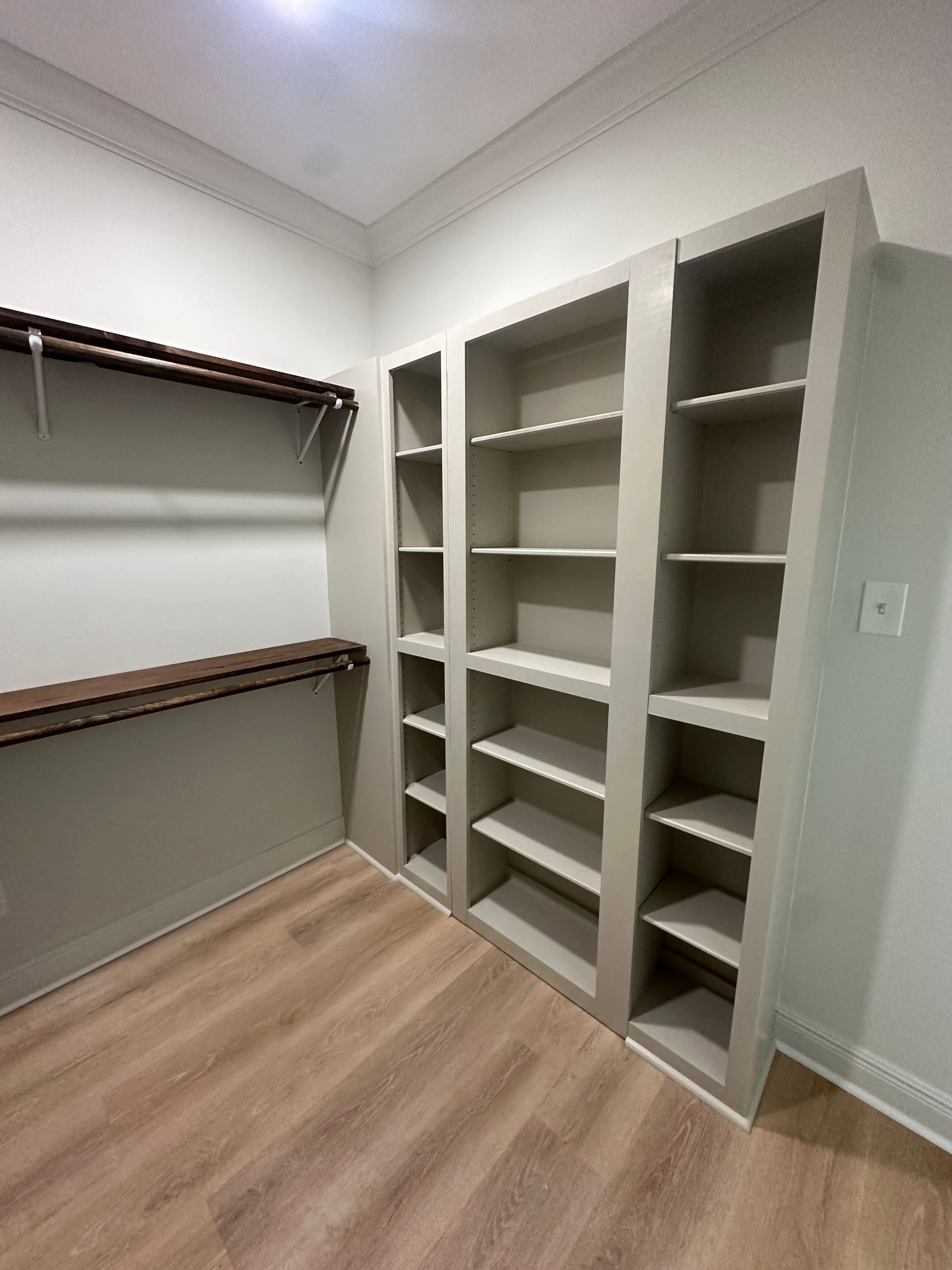 A walk in closet with lots of shelves and a wooden floor.