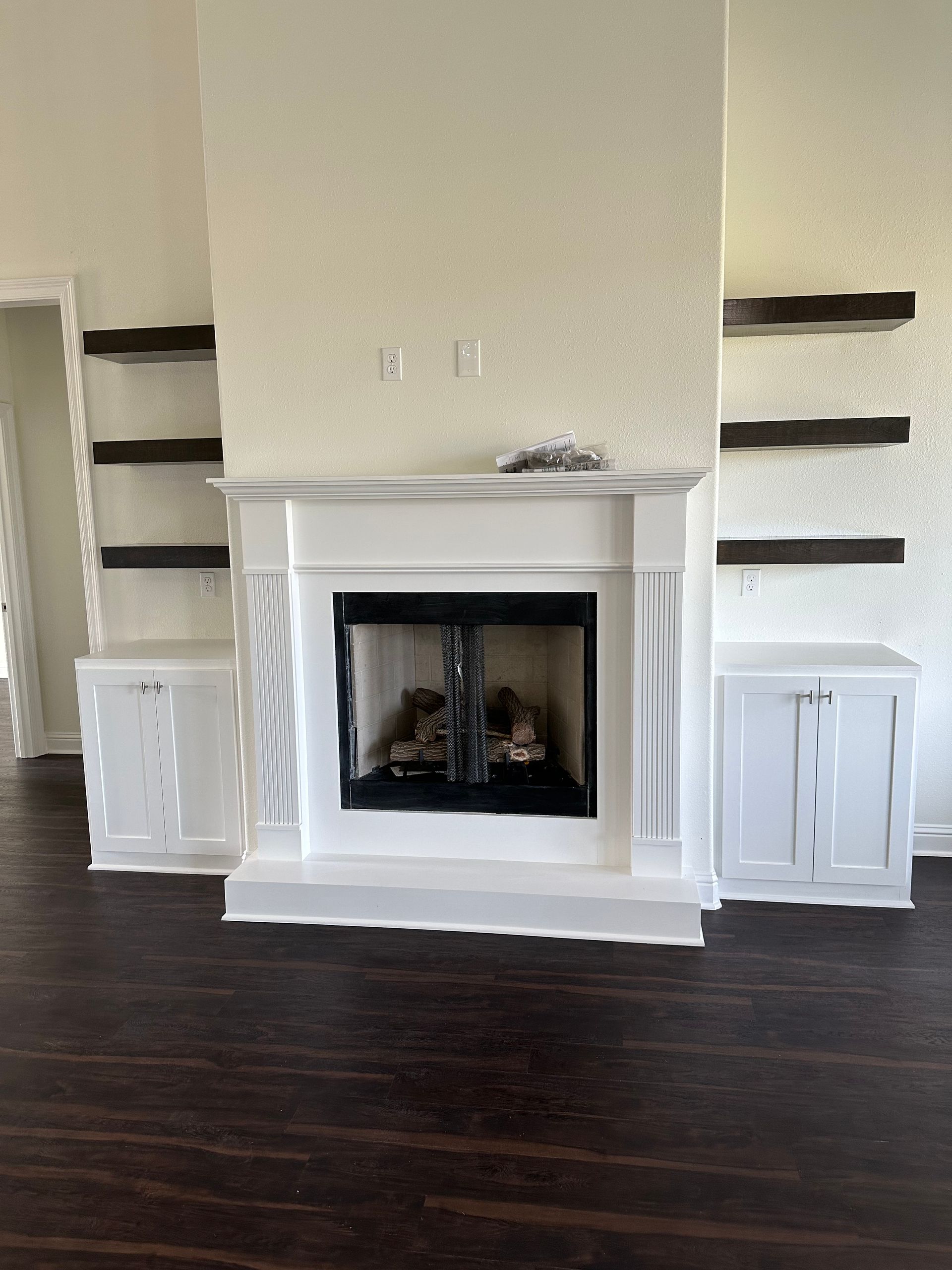 An empty living room with a fireplace and shelves