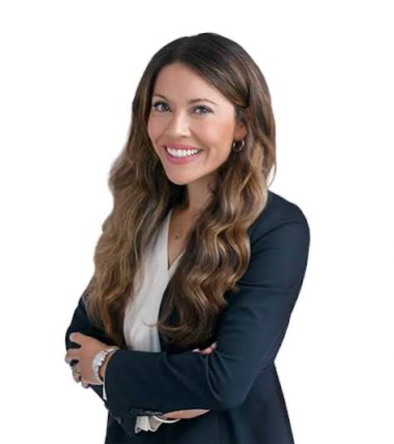 A woman with long brown hair in a blue blazer smiles in front of a white background.