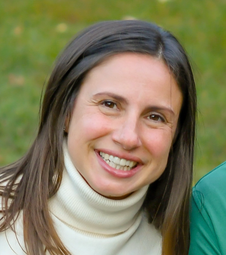 A smiling dark haired woman wearing a white turtleneck.