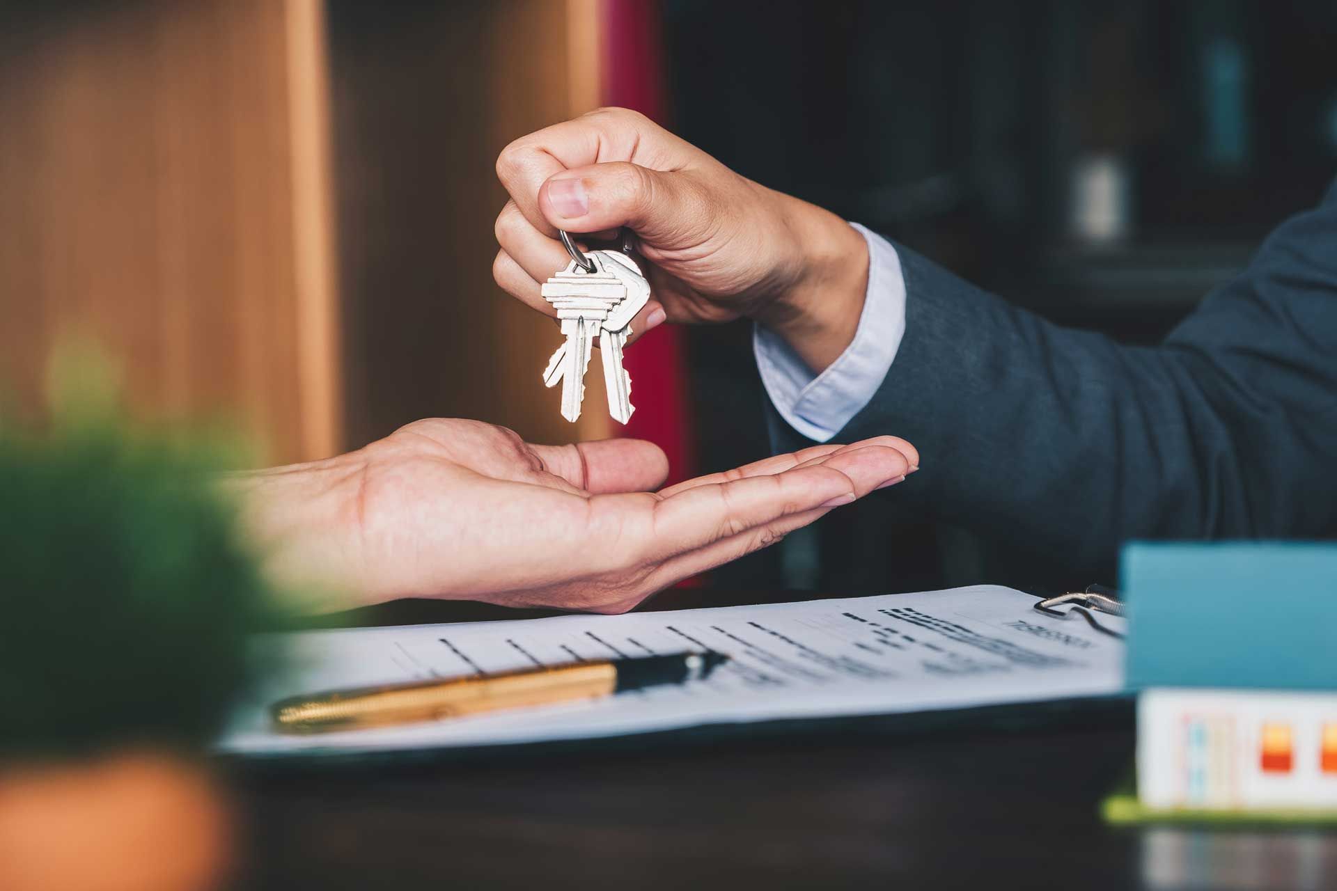 A man is handing a set of keys to another man.