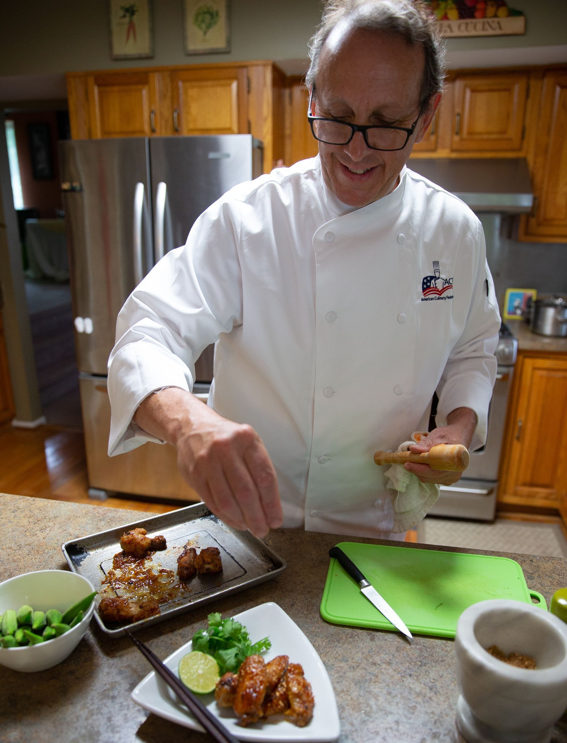 A man in a chef 's uniform is preparing food in a kitchen.