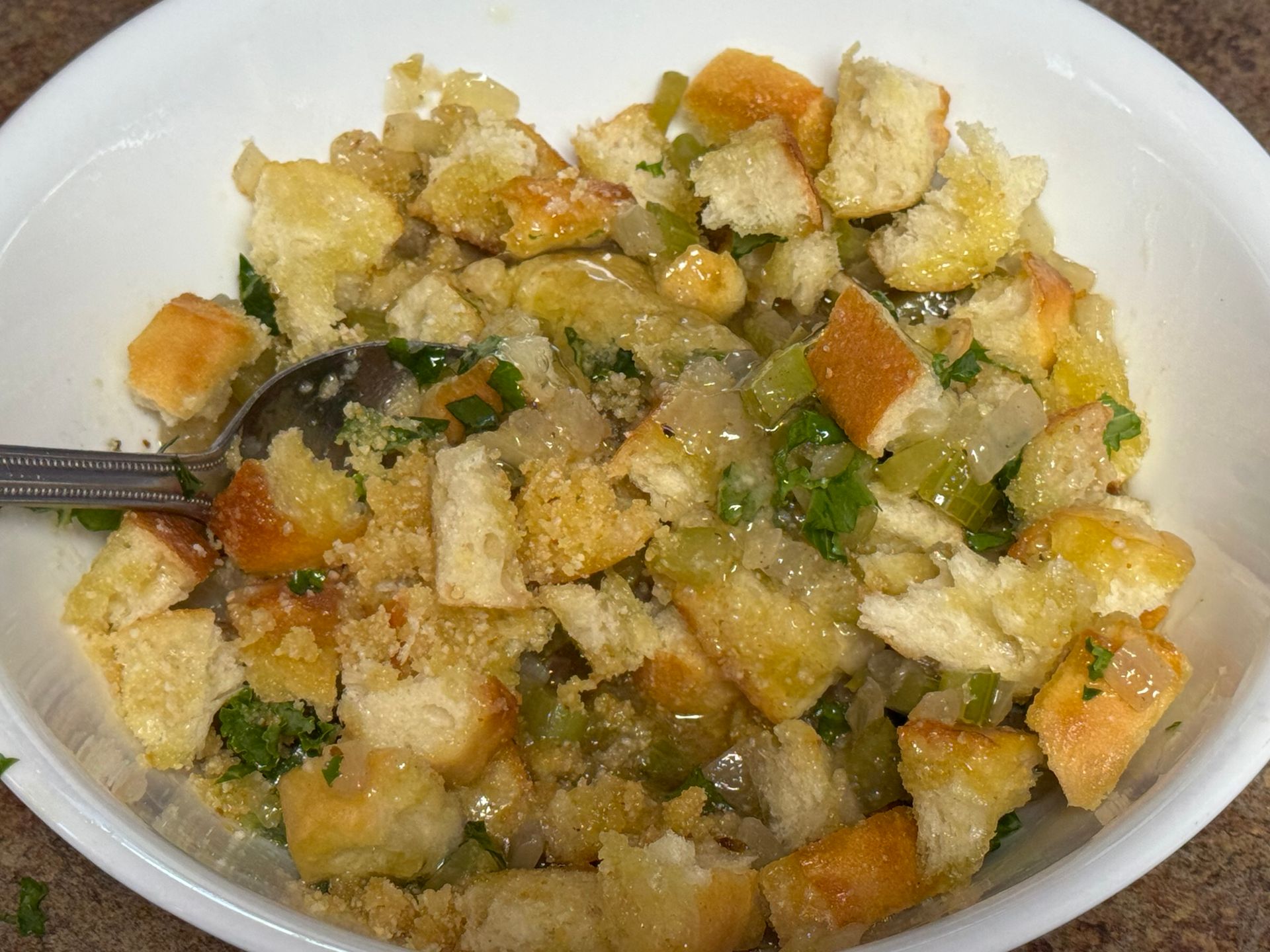 A close up of a bowl of stuffing with bread and vegetables.
